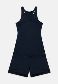 Musta urheilullinen toppi, jossa on kilpailujatkeinen muotoilu ja yhteensopivat shortsit, valmistettu kosteutta siirtävästä kankaasta, sileä rakenne ja tasaiset saumat.