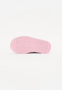 Svarta skor med en texturerad gummisula som har en rosa ytterdel. Sula har ett geometriskt mönster för grepp och flexibilitet.