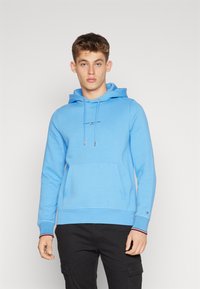 Felpa con cappuccio azzurro chiaro realizzata in tessuto morbido, con tasca a marsupio, cappuccio con cordino e logo sul petto. Polsini ribbed con accenti rossi e bianchi.