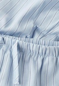 Tissu bleu clair avec des rayures blanches verticales, doté d'une taille élastique et d'un cordon de serrage pour un ajustement personnalisable. Texture lisse.
