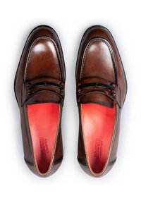 Brown leather loafers with a glossy finish, featuring a black accent band and red interior lining. Sleek, rounded toe design.