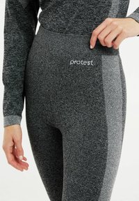 Leggings grigi in tessuto testurizzato, con una fascia in vita liscia e un pannello laterale a motivo a contrasto. Logo visibile in vita.