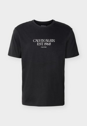 Μαύρο T-shirt με κοντά μανίκια και λευκό κείμενο "Calvin Klein EST. 1968" στο κέντρο του στήθους σε γραμματοσειρά serif.