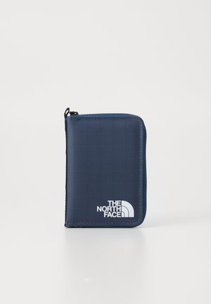 Compact navy blue zippered wallet with grid pattern and white "The North Face" logo on a plain light background.