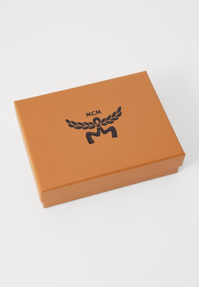 Cutie portocalie cu o finisare netedă, având un logo MCM negru și un design de lauri. Cutia are o formă rectangulară și dimensiuni compacte.