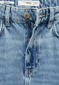 Denim jeans with a light blue wash, featuring a metal button closure, zipper, and contrast stitching. Pockets integrated into the design.