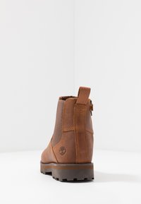 Bottine en cuir marron avec des panneaux élastiques sur les côtés et une languette de tirage. Dispose d'une semelle texturée et d'un logo à l'arrière.
