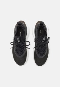 Black athletic sneakers featuring a textured mesh upper, contrast gray accents, round laces, and a thick white sole.