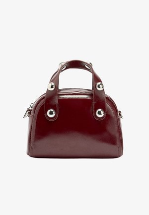 Błyszcząca burgundowa skórzana torebka o zaokrąglonym kształcie, z dwoma górnymi uchwytami i srebrzystymi okrągłymi ozdobami. Zapięcie na suwak u góry.