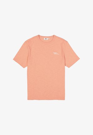 Camiseta de manga corta color durazno, hecha de tela suave, con cuello redondo y un pequeño logo blanco estampado en el pecho.