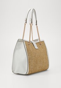 Spleciona torba na ramię z siana z białymi skórzanymi bokami, złotymi łańcuszkami na rączkach oraz białą skórzaną klapką na tle jednolitym.