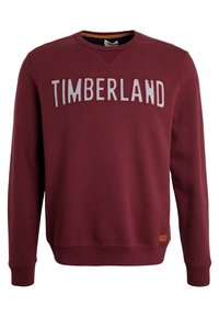 Felpa bordeaux con "TIMBERLAND" ricamato sul petto in grigio, dotata di maniche lunghe e scollatura rotonda. Tessuto morbido.