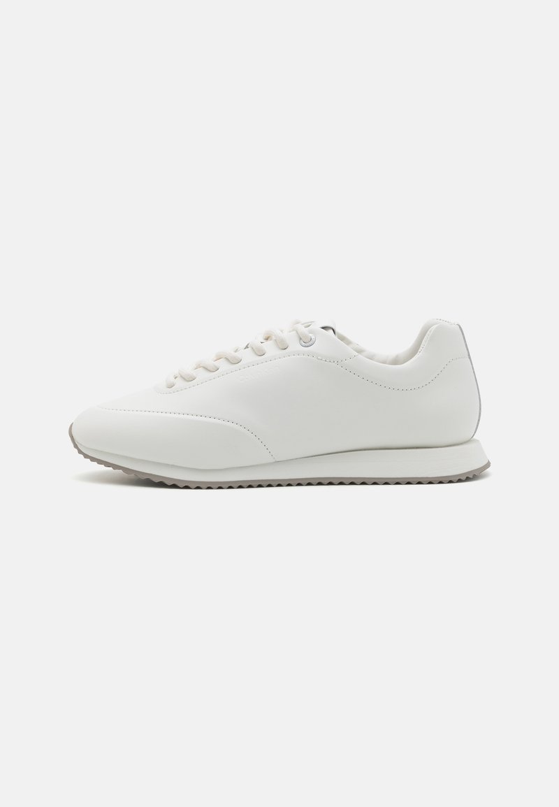 Hvite sneakers laget av glatt lær med rund tå, snøring, en polstret krage og en teksturert gummisåle.