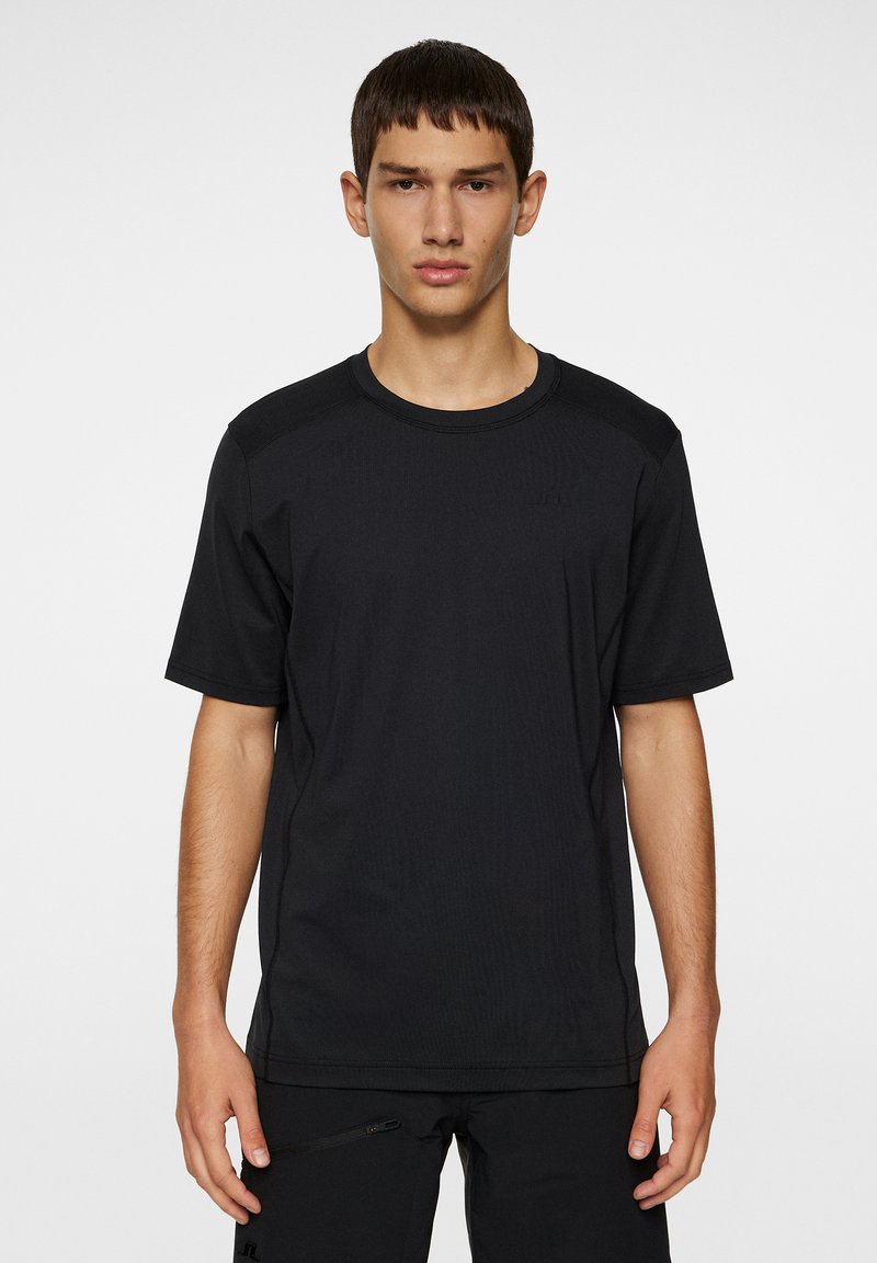 Svart kortärmad atletisk t-shirt i lätt material, med rund hals och en subtil präglad logotyp på övre vänstra sidan.