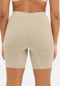 Bermudas de control de cintura alta en color beige, fabricadas con material elástico, que presentan una textura suave, un diseño ajustado y minimalistas detalles de costura.