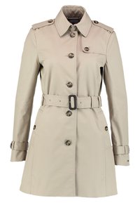 Trench-coat beige longueur genoux avec fermeture à boutons, taille ceinturée, épaulettes et sangles aux poignets.