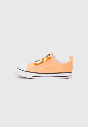 Orange fuzzy slip-on shoes with a cartoon face design, black and white striped sole, and a white toe cap. Soft texture and rounded shape.
