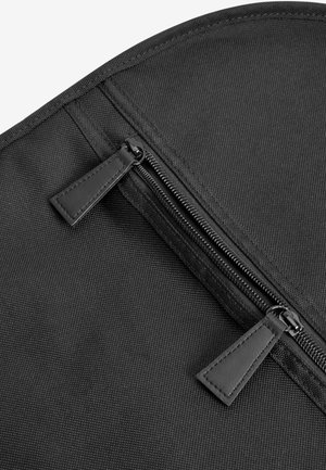 Borsa nera in tessuto con superficie testurizzata, chiusura con zip e accessori in metallo nero, oltre a linguette in pelle coordinate.