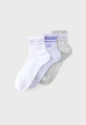 Trois chaussettes de cheville blanches, violet clair et grises avec des rayures assorties et un logo New Balance sur les bords-côtes.