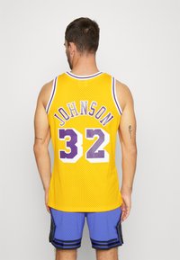 Maglia da basket gialla con accenti viola, con "JOHNSON" e il numero "32" sul retro. Realizzata in tessuto a maglia traspirante, design senza maniche.