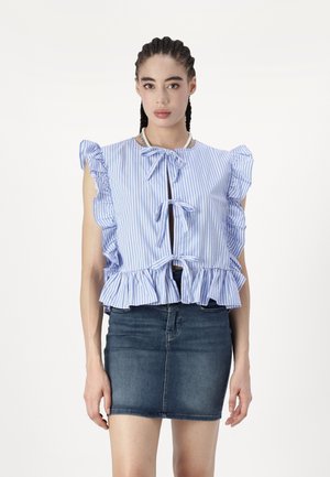 Crop top rayé bleu et blanc avec de courtes manches à volants, des accents en forme de nœud et un ourlet évasé. Assorti à une jupe mini en jean.