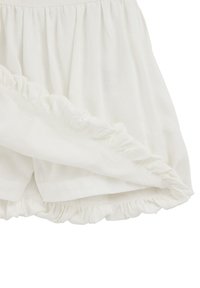 White, lightweight fabric with a ruffled hem and elastic waistband; gathered texture with a soft, flowing appearance.