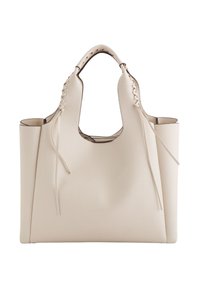 Beige læder tote taske med en struktureret overflade, åben top, bredt design, udskårne håndtag og dekorativ snøre detaljer på siderne.