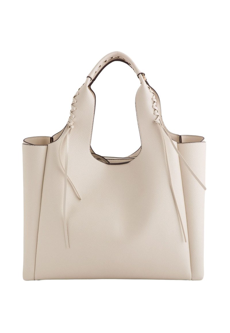 Beige læder tote taske med en struktureret overflade, åben top, bredt design, udskårne håndtag og dekorativ snøre detaljer på siderne.