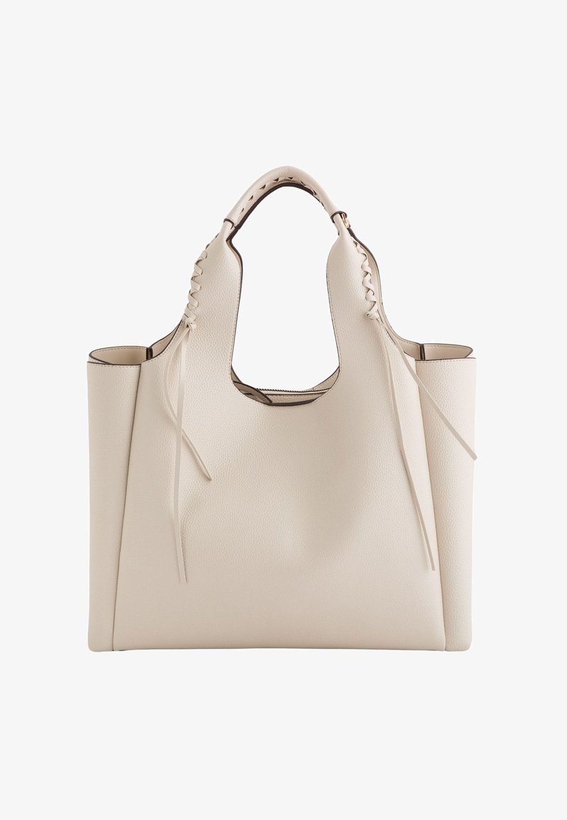 Beige læder tote taske med en struktureret overflade, åben top, bredt design, udskårne håndtag og dekorativ snøre detaljer på siderne.