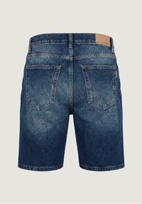Vista trasera de unos shorts de mezclilla azules con dos bolsillos de parche, un pasador para cinturón y una etiqueta de cuero con la marca en la pretina.