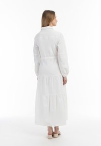 Hvid langærmet maxikjole med lagdelt design, krave og elastisk talje. To lavet af letvægtsstof; glat tekstur, kanten lige over anklerne.