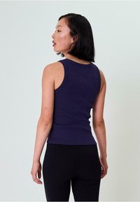 Granatowy, prążkowany top bez rękawów o dopasowanym kroju, z szerokimi ramiączkami i zaokrąglonym dekoltem, zestawiony z czarnymi dopasowanymi legginsami.