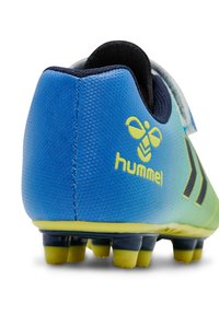 Chaussure de football bleue et verte avec une tige synthétique texturée, accents noirs, logo jaune, et crampons robustes pour une meilleure traction.
