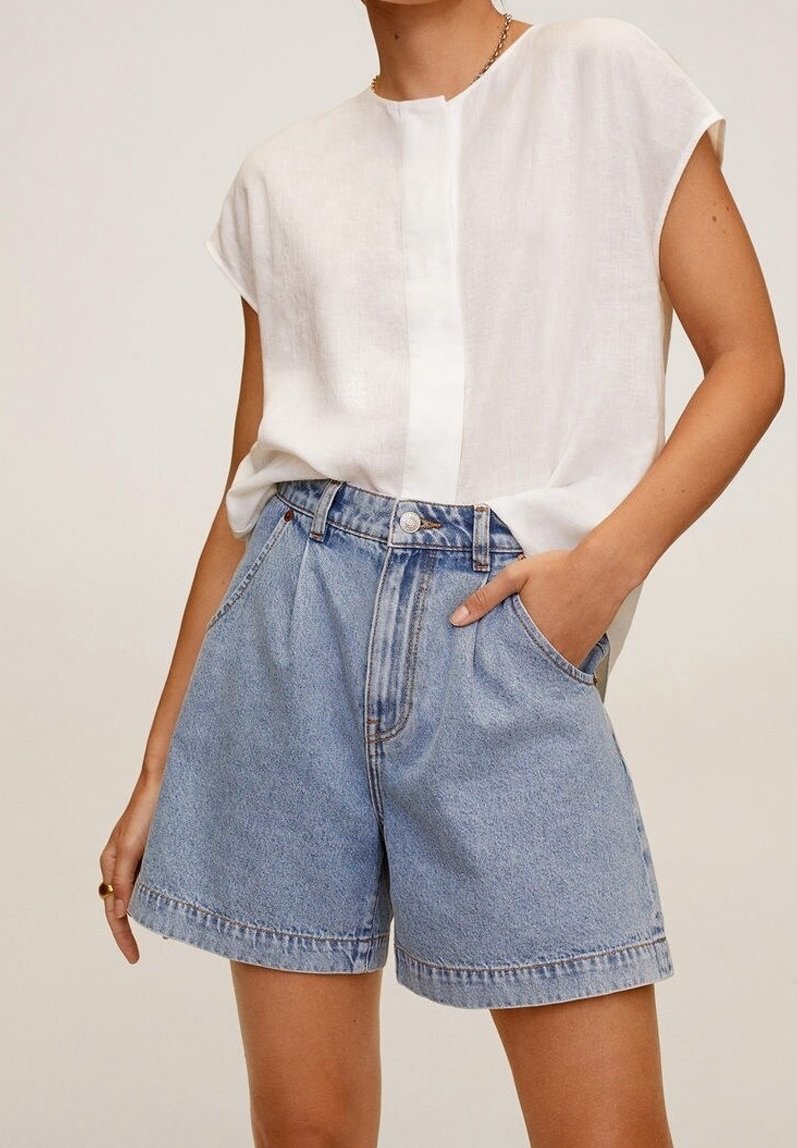 Un haut en lin blanc à manches courtes, associé à un short en denim taille haute de couleur bleu clair, avec des poches latérales et une coupe décontractée.