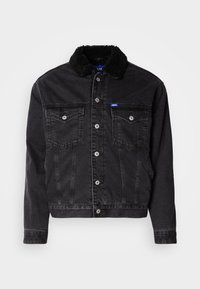 Chaqueta de mezclilla negra con un suave cuello de piel negra, dos bolsillos en el pecho, cierres de botones plateados y un diseño ligeramente corto.