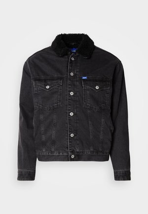 Veste en denim noir avec un col en fausse fourrure noire douce, deux poches poitrine, fermetures à boutons argentés et une coupe légèrement raccourcie.