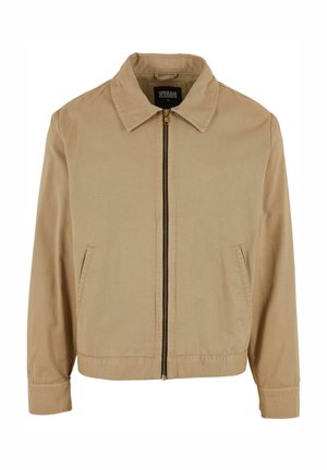 Beige Steppjacke mit klassischem Kragen, zwei Seitentaschen und langen Ärmeln. Hergestellt aus Baumwolle mit glatter Textur.