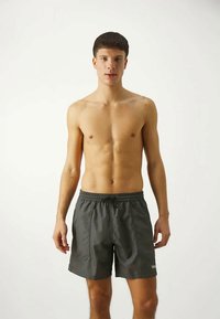 Μαγιό σορτσάκι σε σκούρο γκρι χρώμα, κατασκευασμένο από ελαφρύ ύφασμα. Διαθέτει ελαστική μέση, πλαϊνές τσέπες και λογότυπο της μάρκας στο κάτω μέρος.