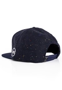 Marineblaues Cap mit einem gesprenkelten Muster, ausgestattet mit einem festem Schirm und einem weißen Logo. Verstellbarer Riemen hinten zur Anpassung der Größe.