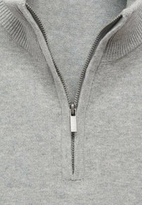 Grå zip-up tröja med stickad textur, med en fjärdedelsdragkedja och ribbad krage. Mjuk tyg med ett subtilt mönster.