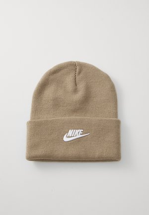 Kreemikas kudumiga müts, millel on volditud serv ja ees valge tikitud Nike logo. Pehme tekstuur ja veniv sobivus.