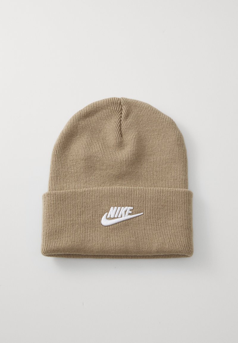Kreminės spalvos megztas beanie kepurė su sulankstytu kraštu, priekyje yra baltas išsiuvinėtas Nike logotipas. Minkšta tekstūra ir tamprus pritaikymas.