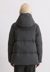 Szara kurtka puchowa z kapturem, o pikowanej konstrukcji i miękkiej, teksturowanej tkaninie. Tył przedstawia prostokątny kształt z widocznym szwem.