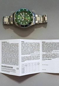 Orologio con quadrante verde, cinturino in acciaio inossidabile e lunetta girevole. Presenta indicatori di ora luminescenti e display della data. Accompagnato da un libretto di garanzia.