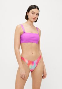 Vijolični bikinij z vrvico za prilagoditev; ustrezni nizkopasovni hlački z živahnim tie-dye vzorcem v roza, modri in zeleni barvi. Gladka textura.