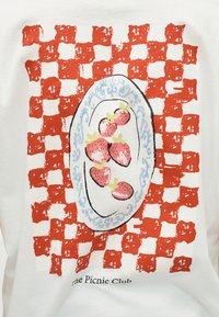 Λευκό ύφασμα με κόκκινο καρό μοτίβο, μπλε και λευκό οβάλ πιάτο που κρατά έξι φράουλες, και κείμενο «The Picnic Club» από κάτω.