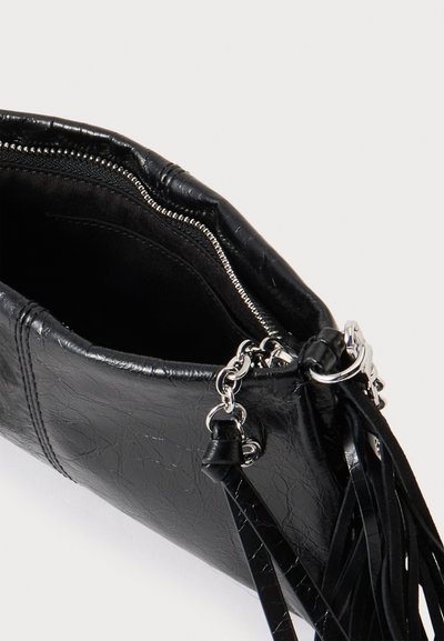 Pochette en cuir noir avec fermeture éclair argentée ouverte montrant l'intérieur, avec une chaîne argentée et des détails de pompon sur le côté.