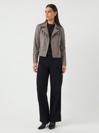 Veste de moto en cuir gris avec fermeture éclair à l'avant, deux poches latérales et col cranté. Associée à un pantalon large noir et des talons hauts.