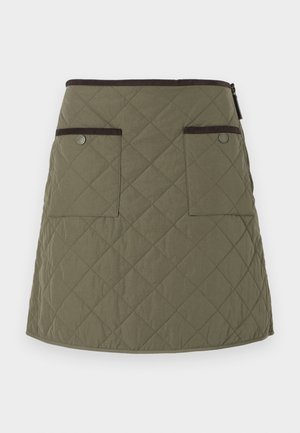 Gequiltede rok in olijfgroen met een zoom die boven de knie valt. Voorzien van twee voorzakken met donkerbruine accenten en een ritssluiting.