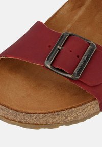 Röd läder sandal med en bred rem och metallspänne, med en korkfotbädd och en strukturerad brun bas.